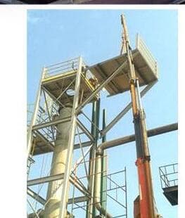 Torre de processo industrial em montagem com plataformas e andaimes